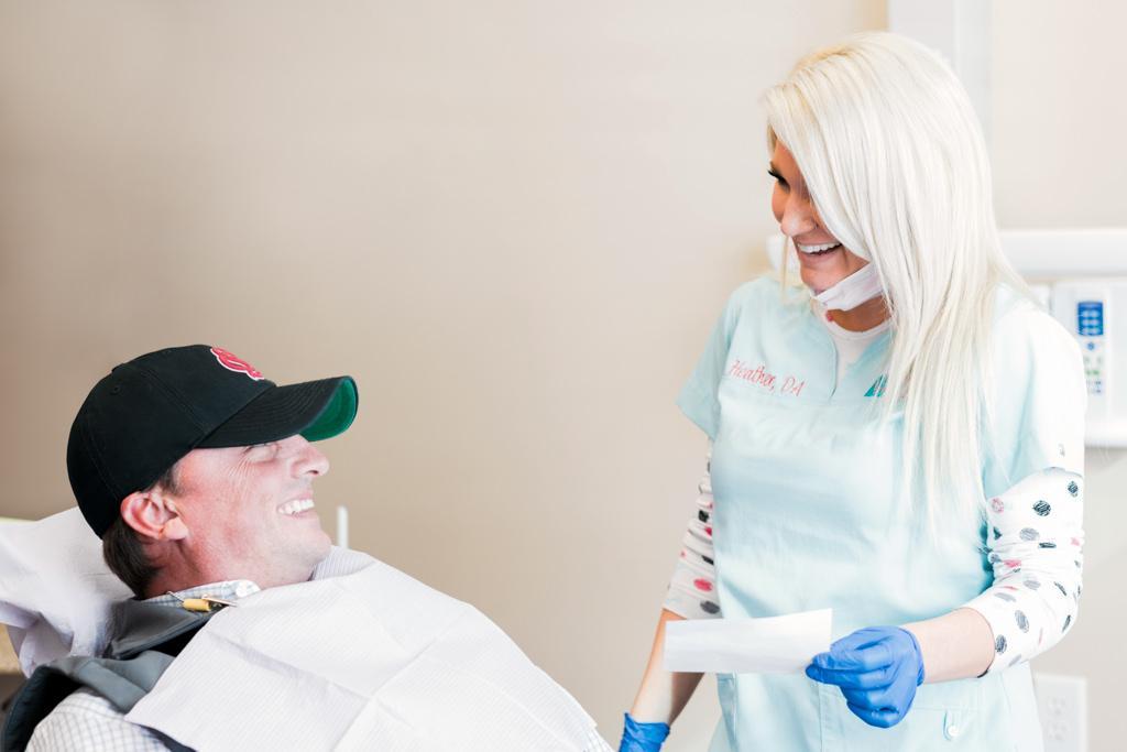 patient in hat looking up and laughing with laughing hygienist